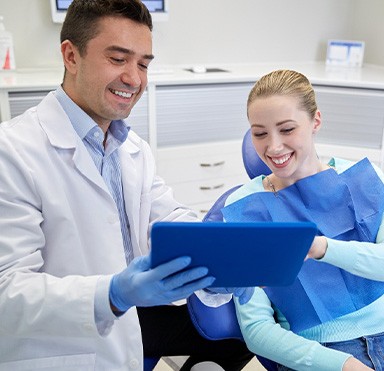 Woman in dental chair signing digital financial forms on tablet