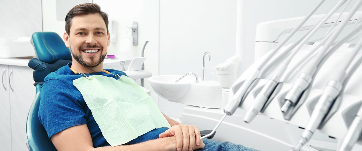 Male patient sitting in dental chair smiling