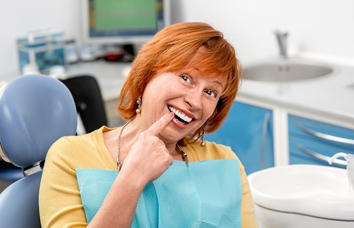 Female patient pointing to smile after dental bonding in Denton, TX