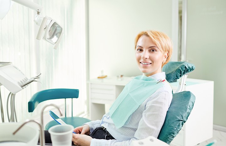 Blonde woman smiling and waiting in dental chair