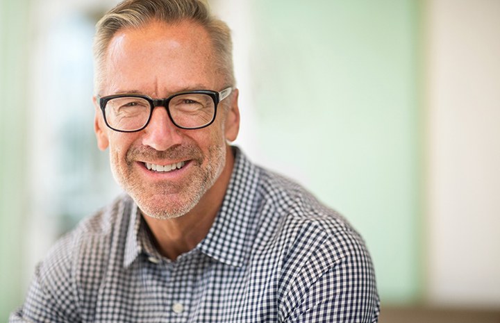 Man with glasses and patterned shirt smiling