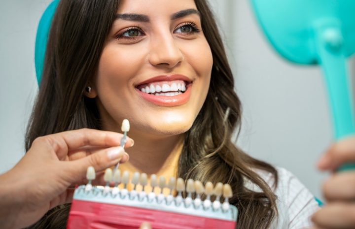 Woman looking at smile after dental bridge restoration