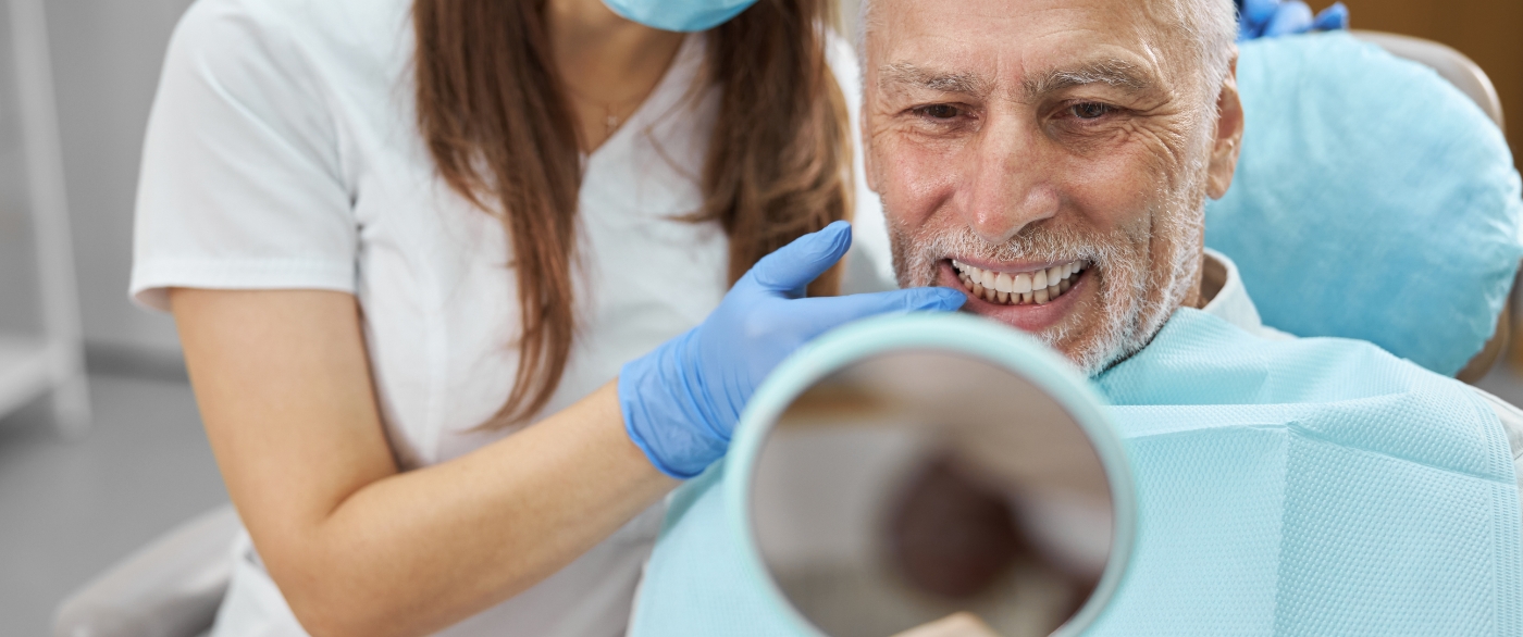 Man looking at smile after tooth replacement with dental implants