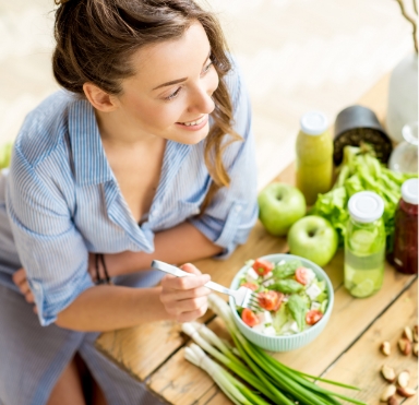 Woman eating a salad after replacing multiple missing teeth