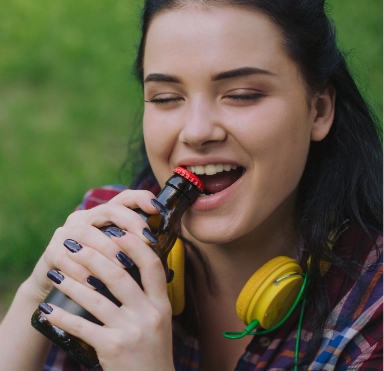 Woman opening a bottle with teeth