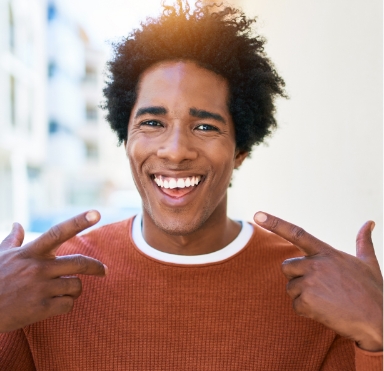 Man with dental implants pointing to smile