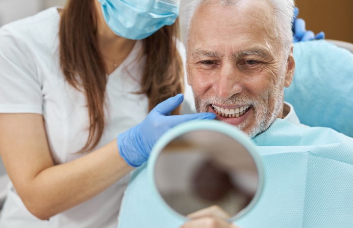 Man looking at smile in mirror after dental implant surgery