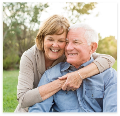 Man and woman with dentures smiling outdoors