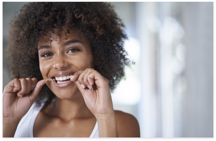 Woman flossing teeth to prevent dental emergencies