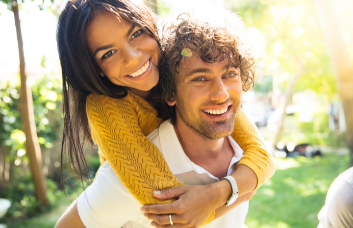 Man and woman sharing bright smiles after teeth whitening