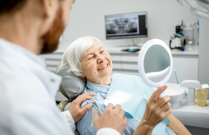 Woman looking at smile after dental implant failure and salvage treatment