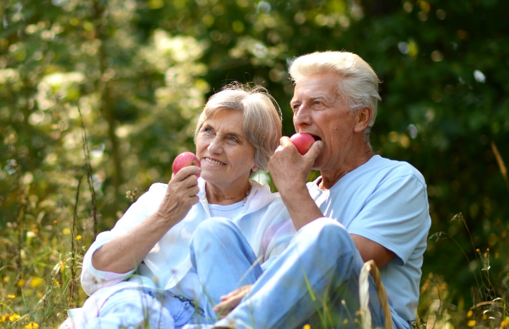 Older couple eating apples together outdoors
