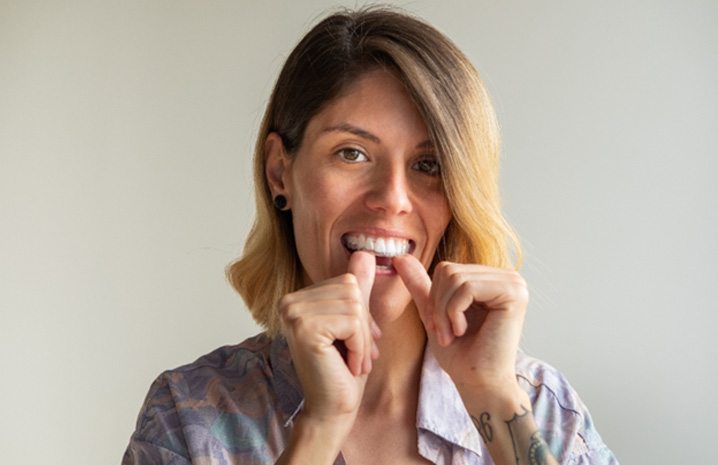 Closeup of woman placing Invisalign aligner in mouth