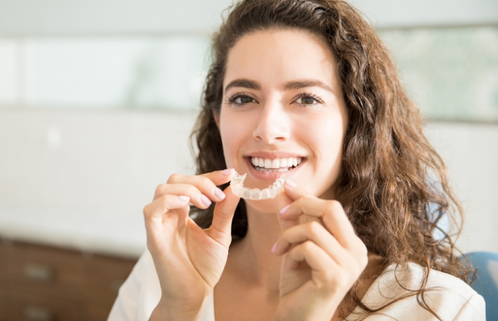 Smiling woman placing an Invisalign tray