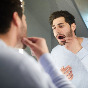 Man examining his teeth in mirror