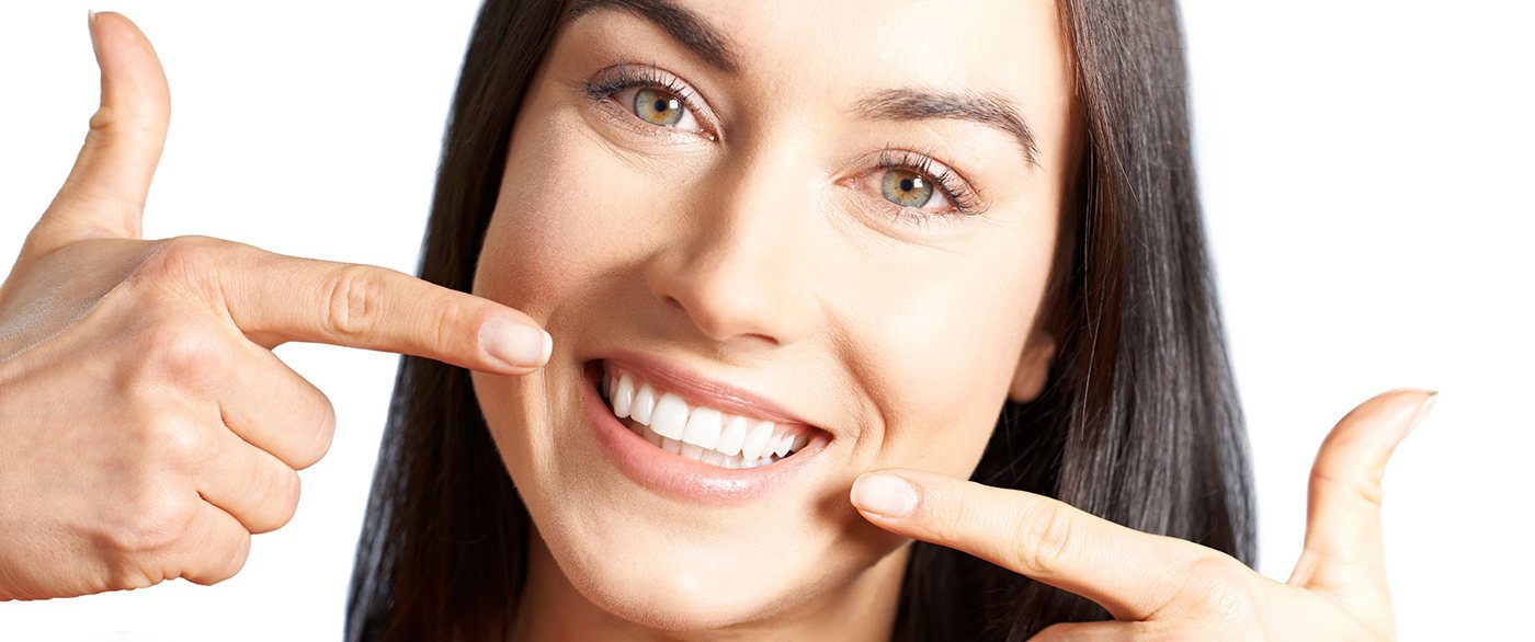 Woman with an attractive smile pointing to her teeth