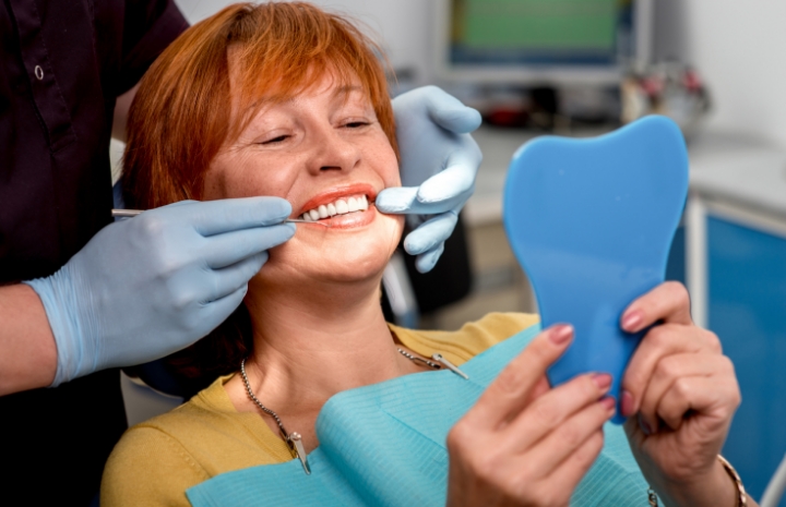 Woman with dentures looking at smile in mirror