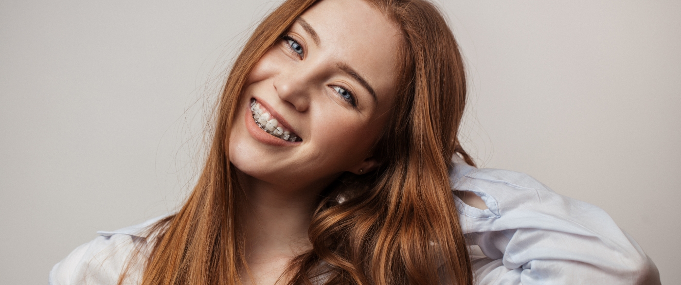 Young woman with traditional orthodontics smiling