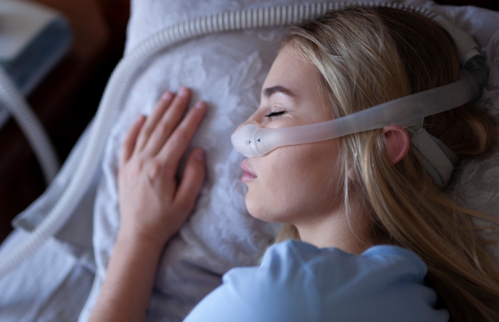 Woman sleeping with CPAP sleep apnea system combined with oral appliance sleep apnea treatment