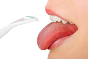 Using a tongue scraper to clean the tongue