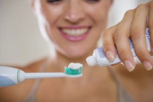 A woman applying toothpaste to a toothbrush.