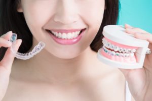 Woman holding braces and Invisalign.