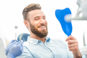 Man smiling into hand mirror